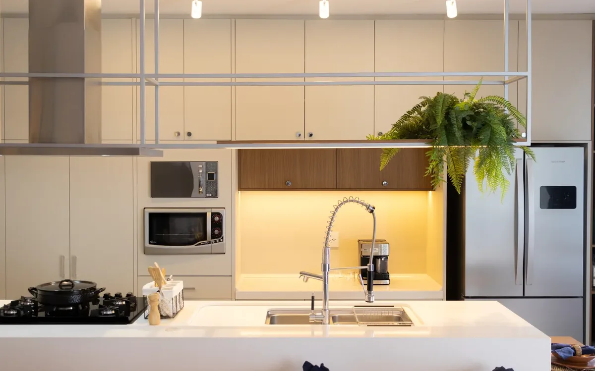 Cozinha planejada com ilha, bancada branca e armários iluminados, projeto entregue em Resende